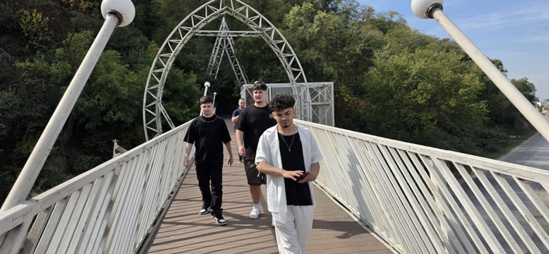 A group of project participants stroll along a wooden bridge in Kaleto Park
