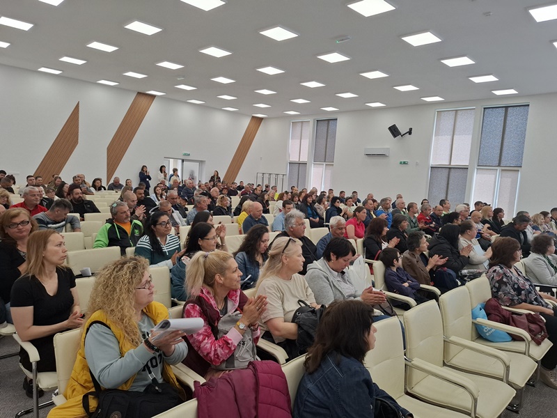 Зала пълна с участници в трудовата борса слушащи презентацията