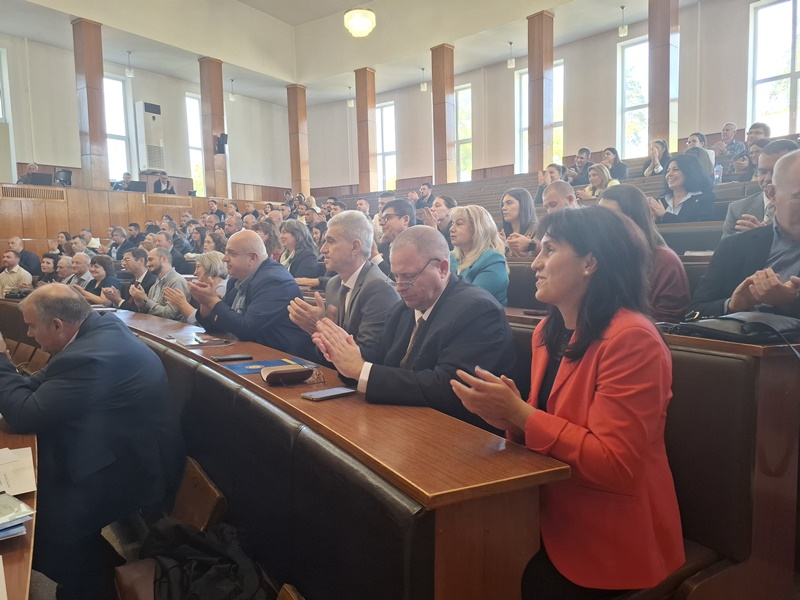 Аплодисменти в конферентна зала по време на честване на 60-годишнината на катедра „Бизнес информатика“. Хората са облечени официално