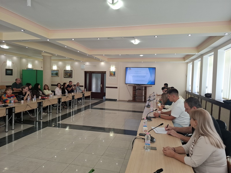 Конферентна зала с участници в дискусия пред презентация за изкуствения интелект и устойчивото развитие
