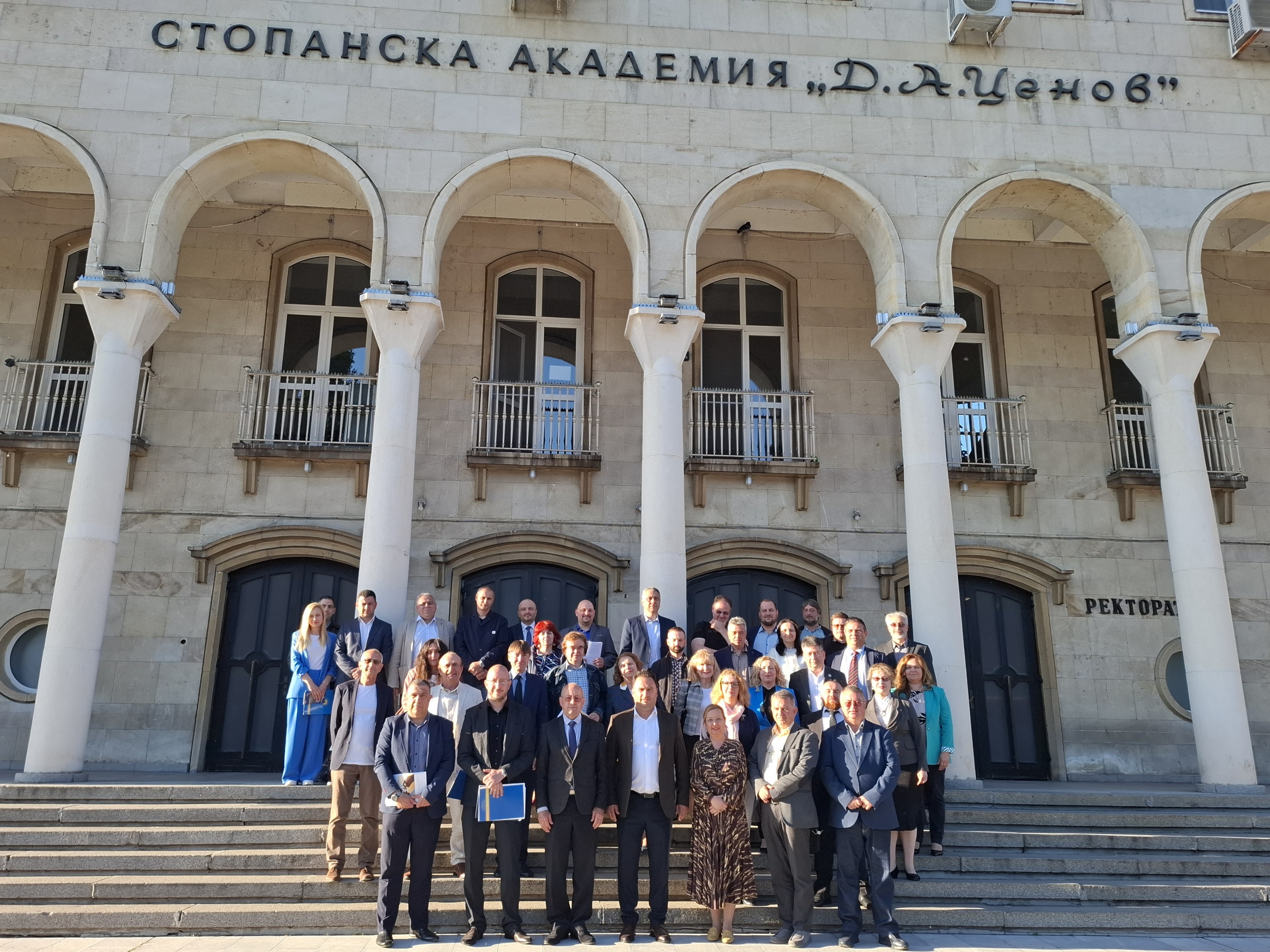 Групова снимка на лауреатите от академията на изкуствата пред фасадата на сградата украсена с колони и надпис „Академия на изкуствата“
