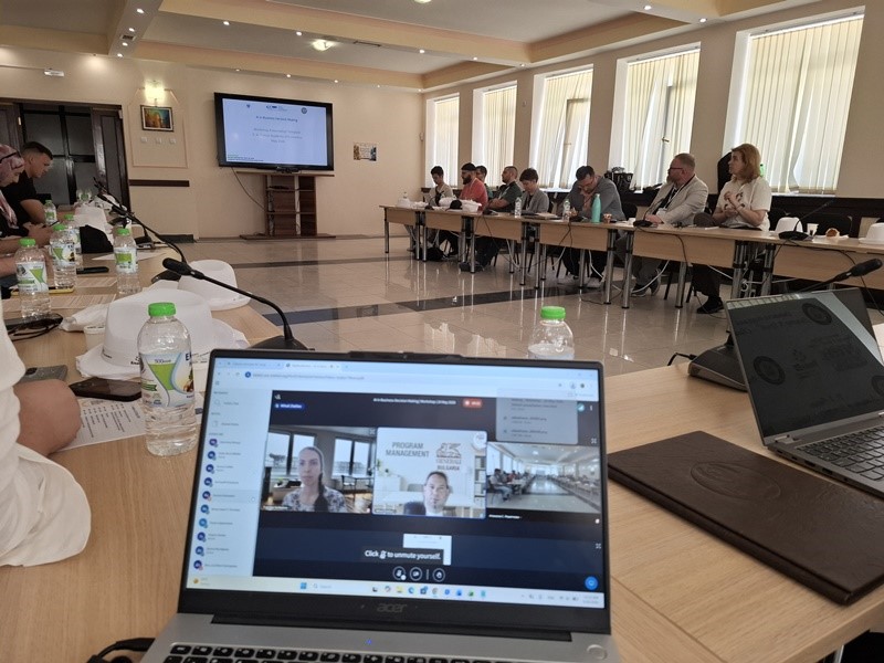A computer on a table with people sitting at tables AI-generated content may be incorrect.